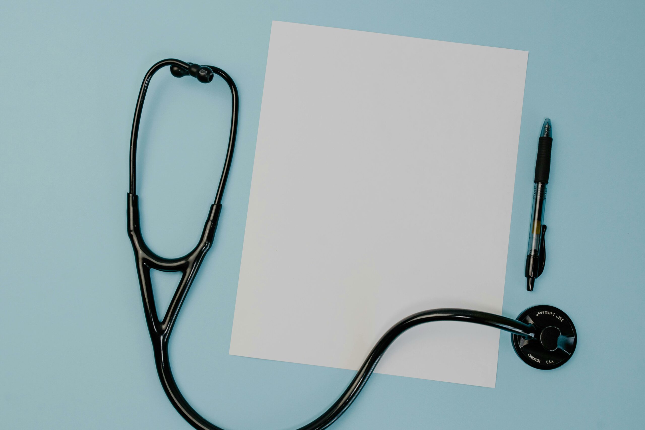 Stethoscope next to a paper and a pen